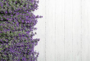 Beautiful tender lavender flowers on white wooden table, top view. Space for text