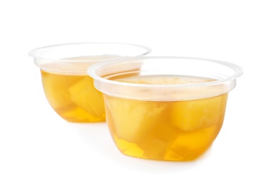 Tasty jelly desserts with slices of fruit in plastic cups on white background