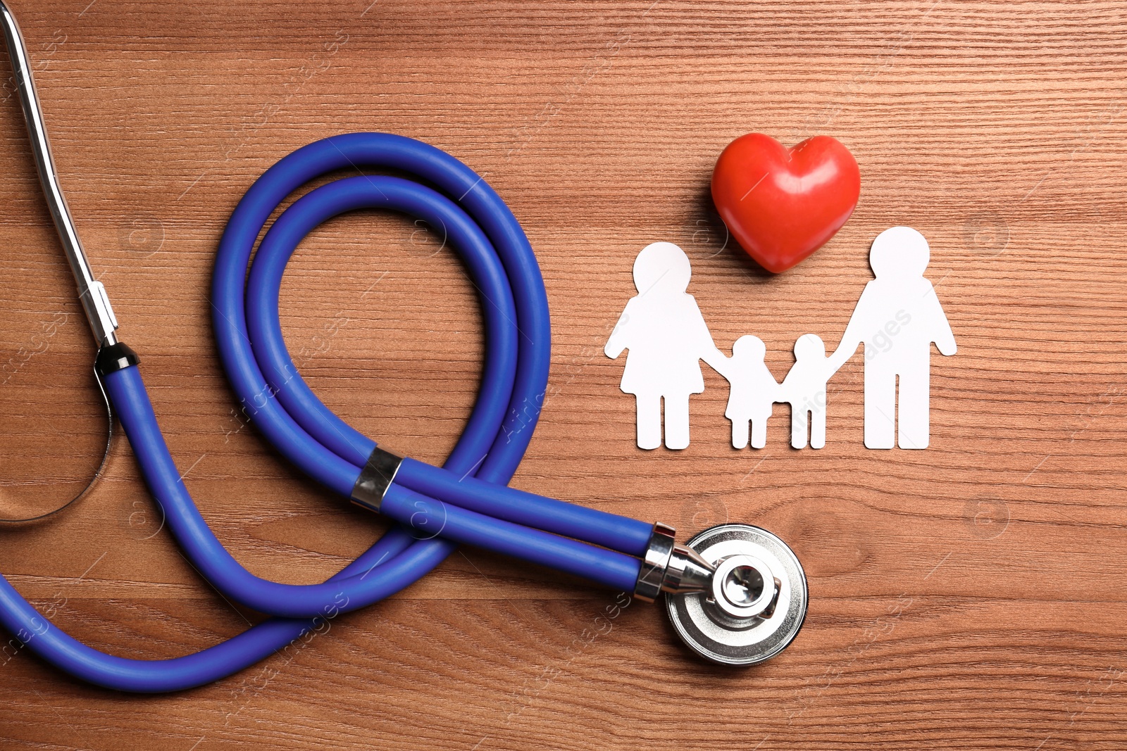 Photo of Flat lay composition with heart, stethoscope and paper silhouette of family on wooden background. Life insurance concept