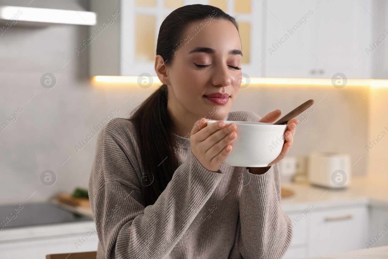 Photo of Woman with bowl of tasty soup in kitchen