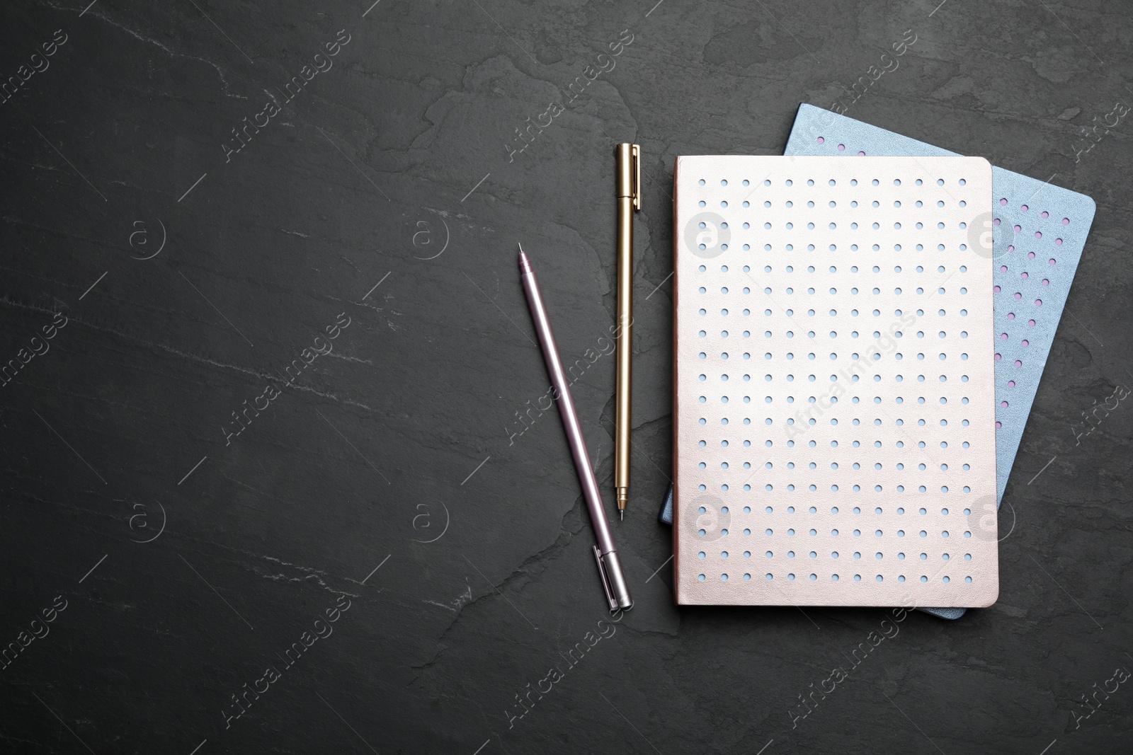 Photo of Stylish notebooks and pens on black table, flat lay. Space for text