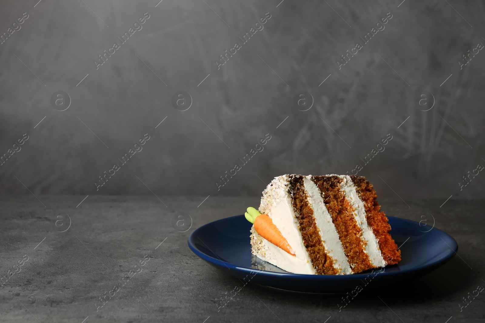 Photo of Plate with piece of carrot cake on grey table, space for text