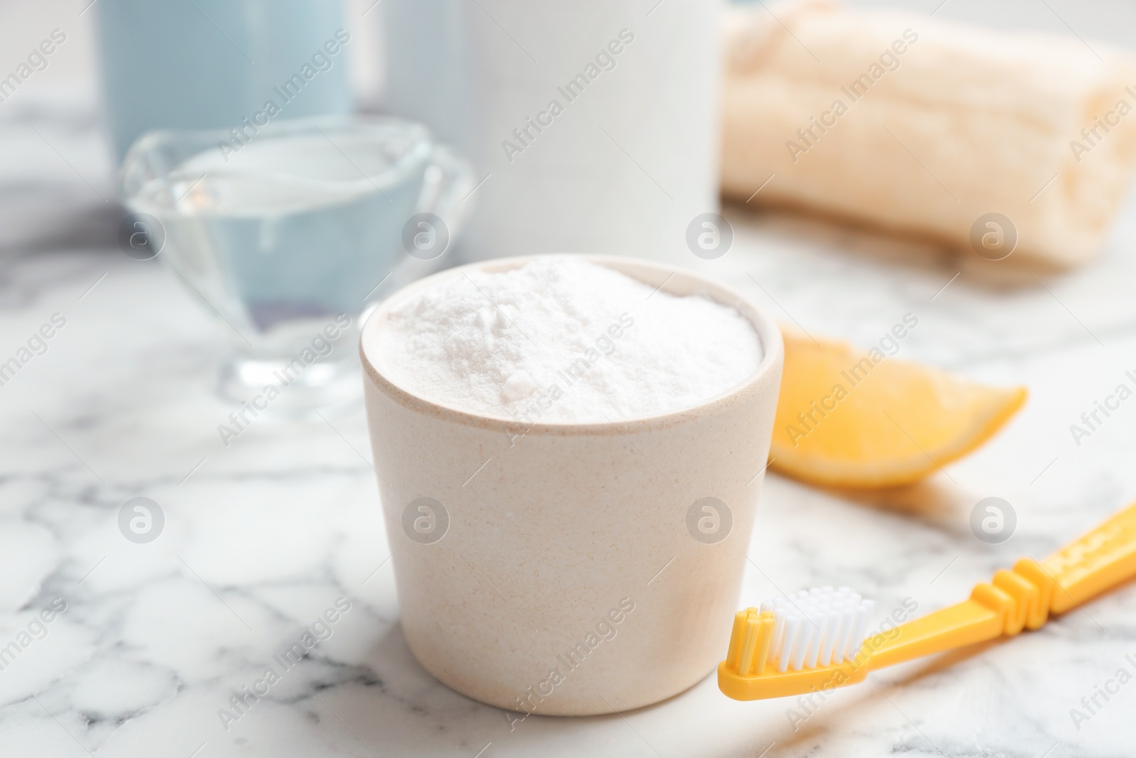 Photo of Bowl with baking soda and toothbrush on marble table