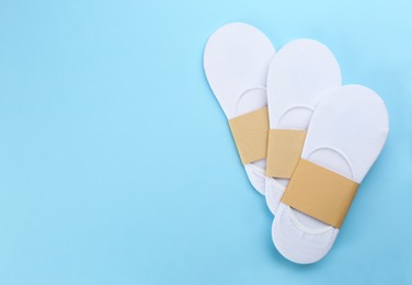 Photo of White cotton socks on light blue background, flat lay. Space for text
