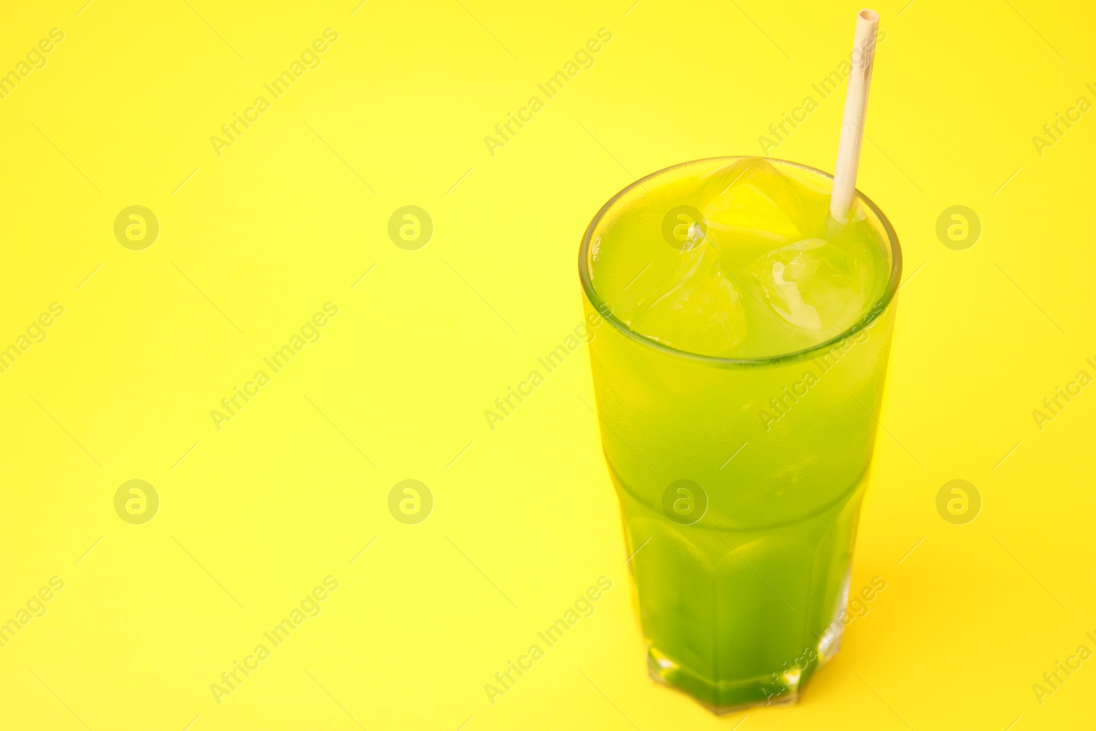 Photo of Glass of delicious iced green matcha tea on yellow background, space for text