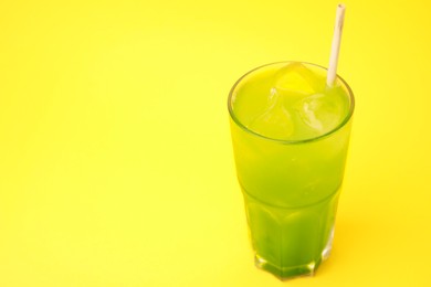 Photo of Glass of delicious iced green matcha tea on yellow background, space for text