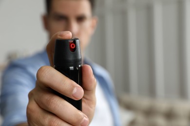 Man using pepper spray at home, focus on hand. Space for text