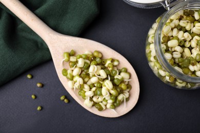 Photo of Wooden spoon with sprouted green mung beans on black background, flat lay