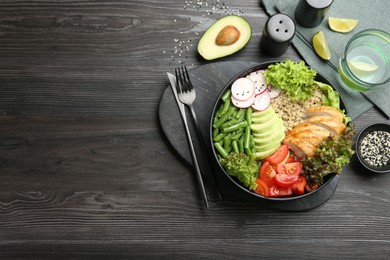 Photo of Healthy meal. Tasty products in bowl and cutlery on black wooden table, flat lay. Space for text