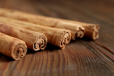 Photo of Aromatic cinnamon sticks on wooden table, closeup
