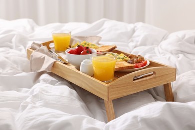 Photo of Good morning. Tray with tasty breakfast on bed at home