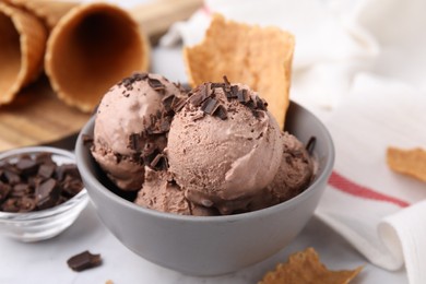 Photo of Bowl of tasty ice cream with chocolate chunks on table, closeup