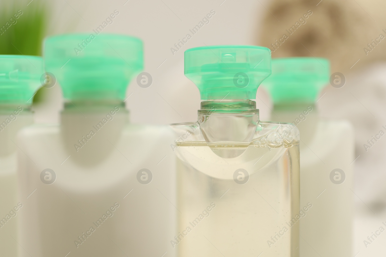 Photo of Mini bottles of cosmetic products on blurred background, closeup