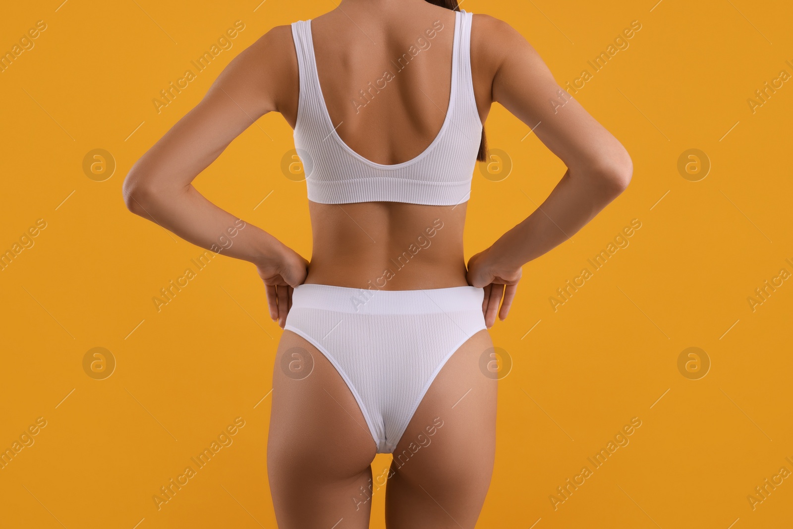 Photo of Young woman in stylish white bikini on orange background, closeup