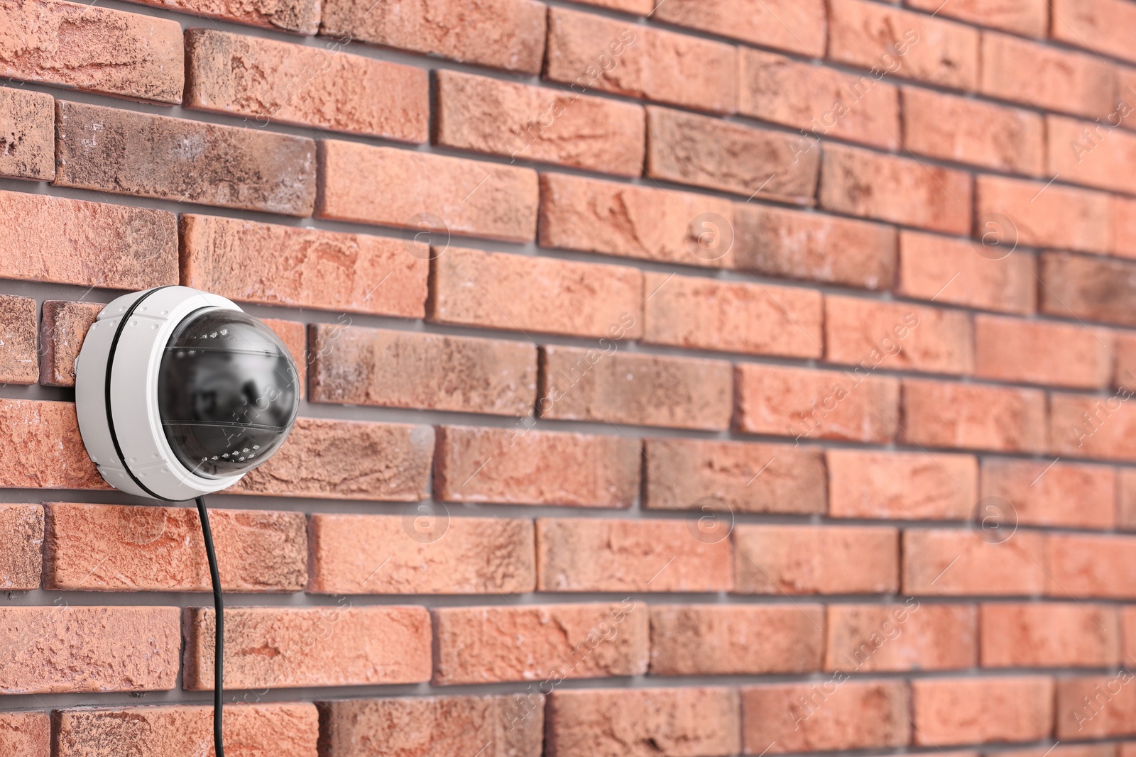 Photo of Modern security CCTV camera on brick wall