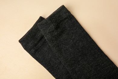 Photo of Black cloth with lint on beige background, top view. Before using fabric shaver