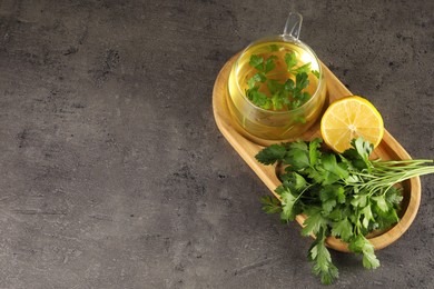 Aromatic herbal tea, fresh parsley and lemon on grey table, top view. Space for text