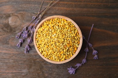 Photo of Fresh bee pollen granules and lavender on wooden table, top view