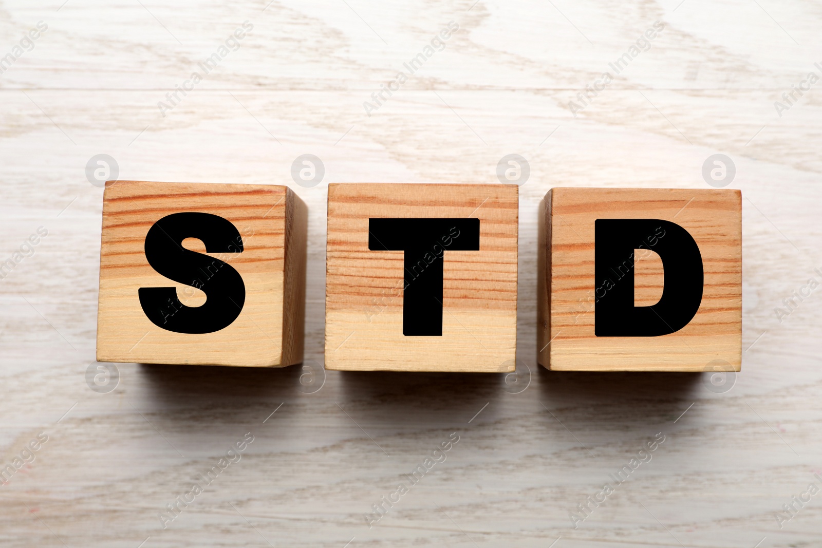 Photo of Abbreviation STD made with cubes on white wooden table, flat lay