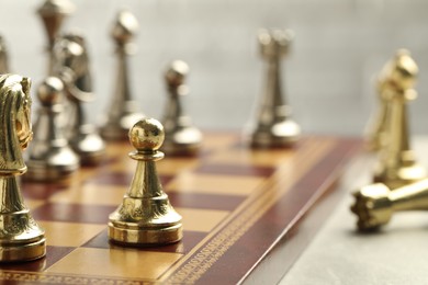 Chessboard with game pieces on light background, closeup. Space for text