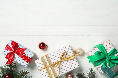 Photo of Gift boxes with Christmas balls and fir branches on white wooden background, flat lay. Space for text