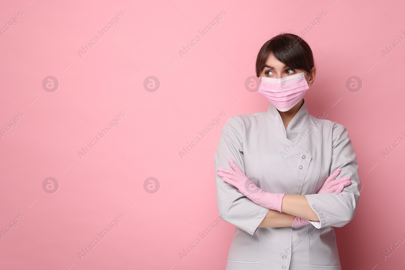 Photo of Cosmetologist in medical uniform on pink background, space for text