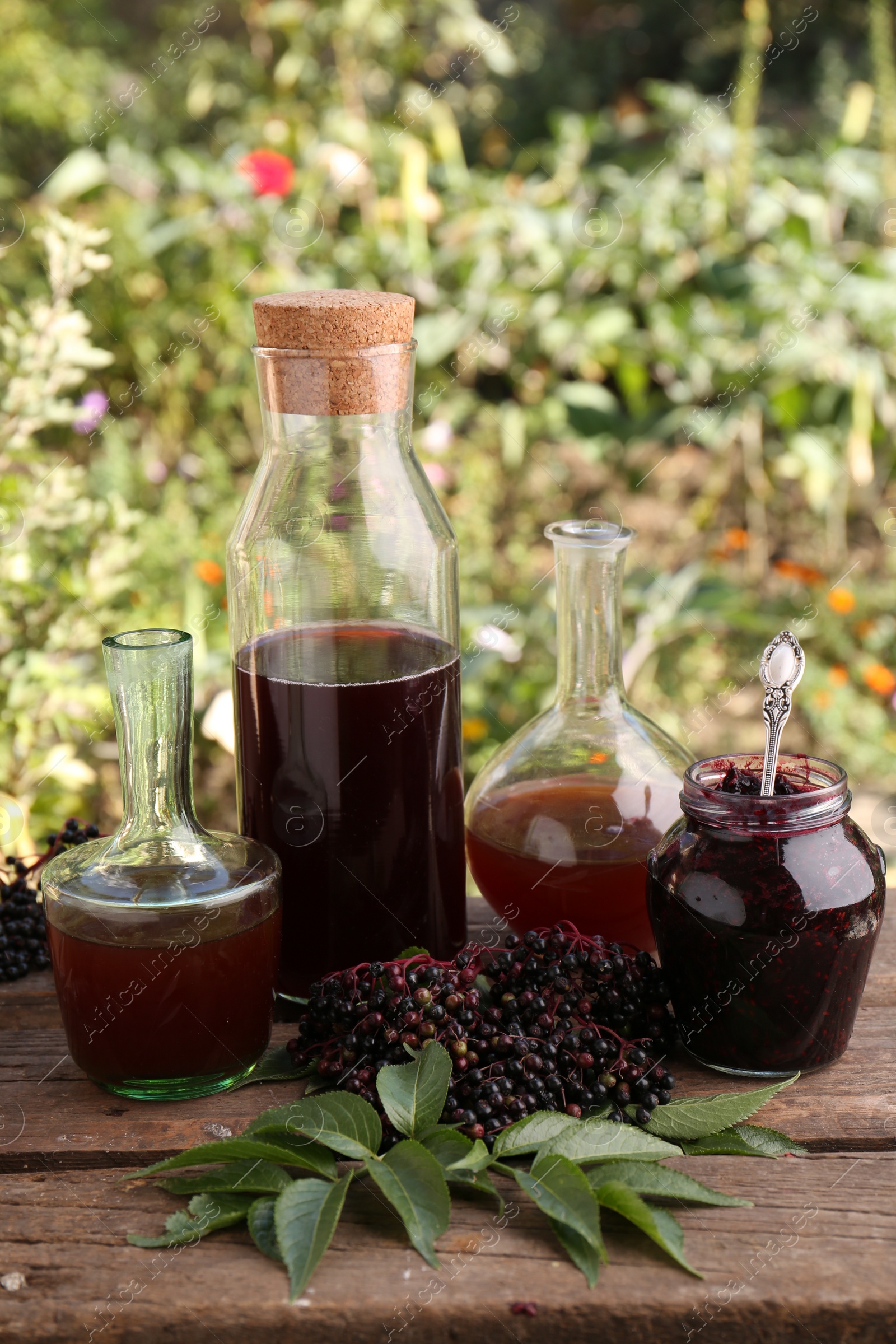 Photo of Elderberry drink and jam with Sambucus berries on table outdoors