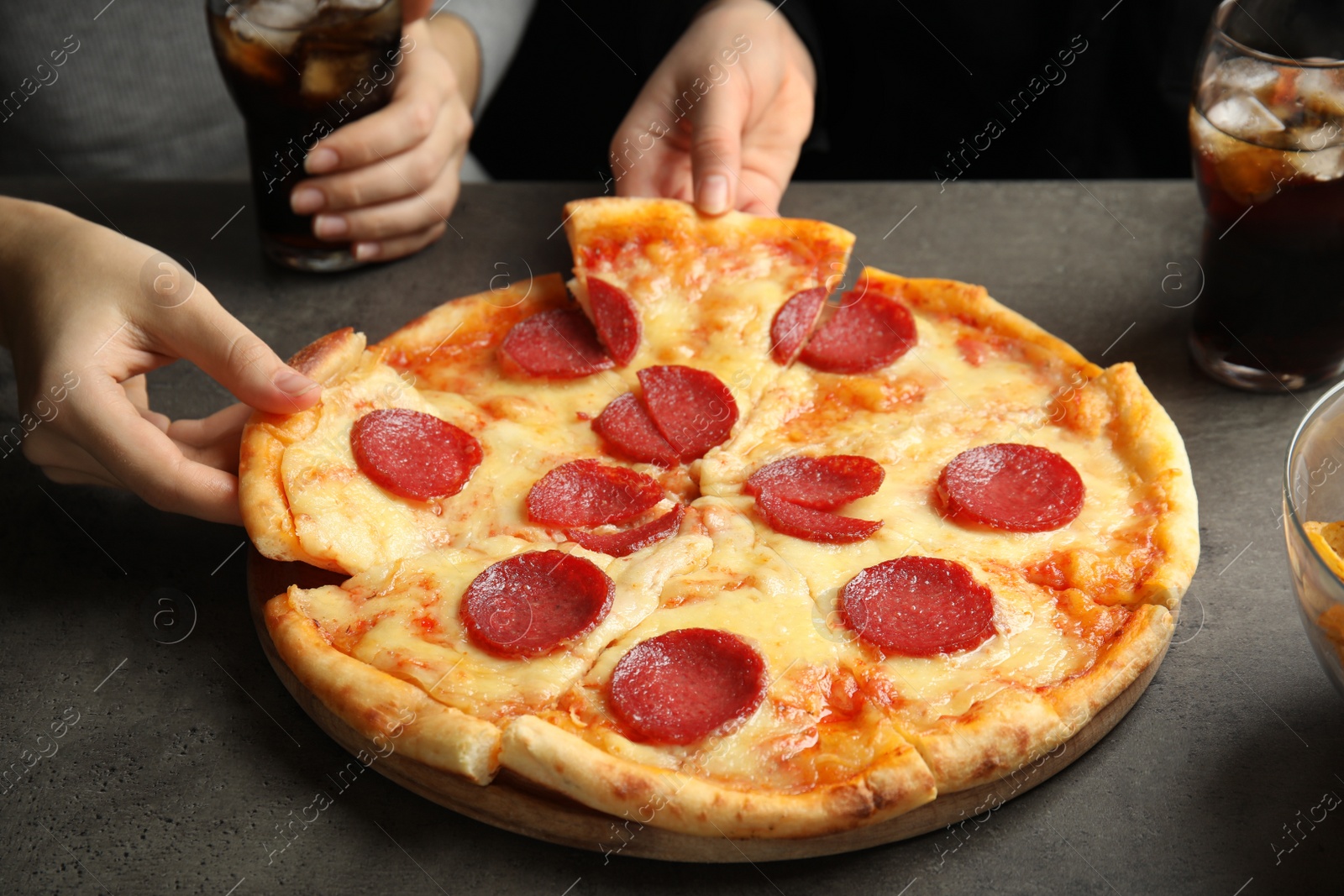 Photo of Women taking tasty pepperoni pizza at grey table, closeup