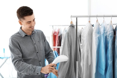 Young man steaming jacket at dry-cleaner's