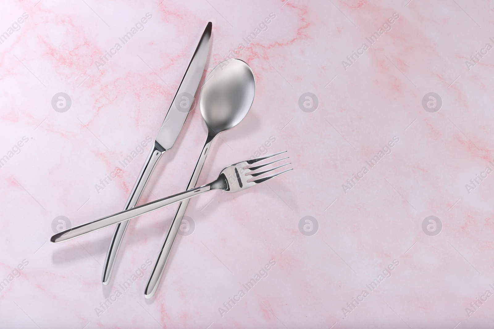 Photo of Stylish cutlery set on pink marble table, flat lay. Space for text