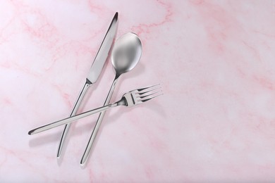 Photo of Stylish cutlery set on pink marble table, flat lay. Space for text