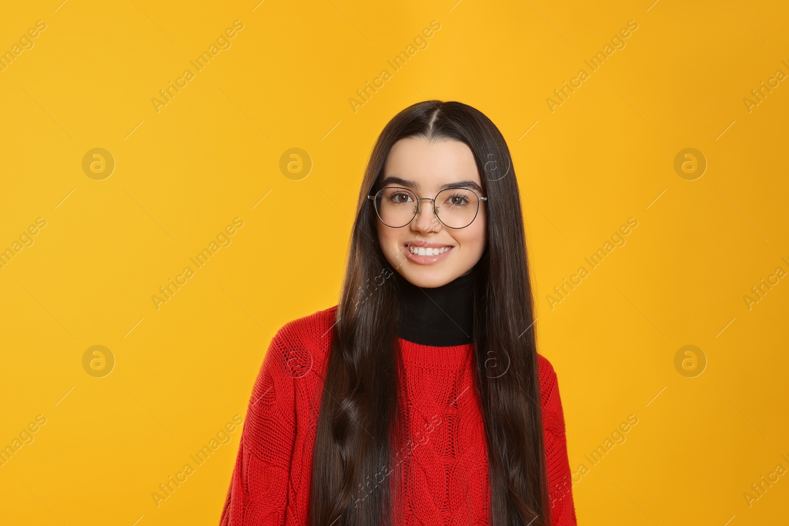 Photo of Portrait of happy teenage girl wearing glasses on yellow background