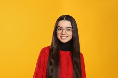 Photo of Portrait of happy teenage girl wearing glasses on yellow background