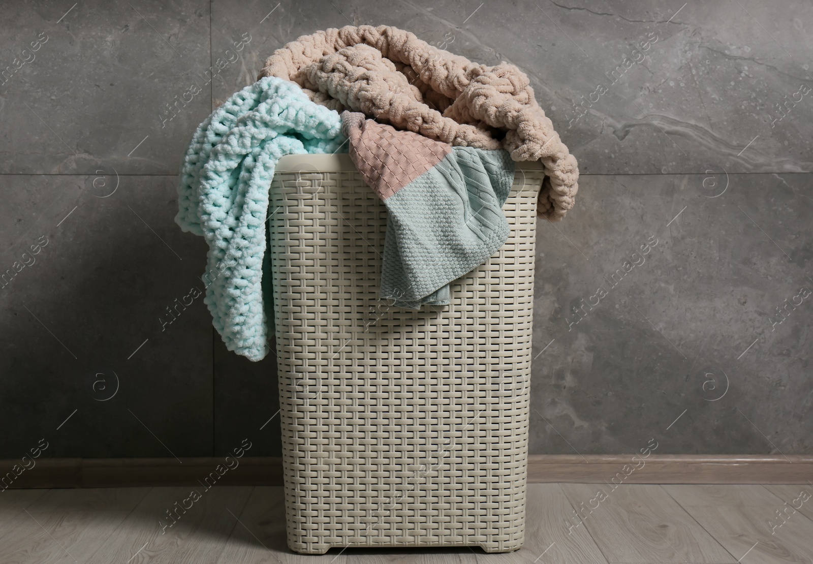 Photo of Laundry basket with clothes near grey wall