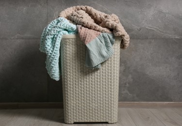 Photo of Laundry basket with clothes near grey wall