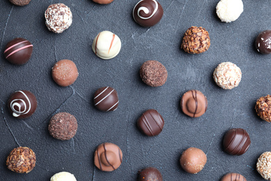 Photo of Different tasty chocolate candies on black table, flat lay