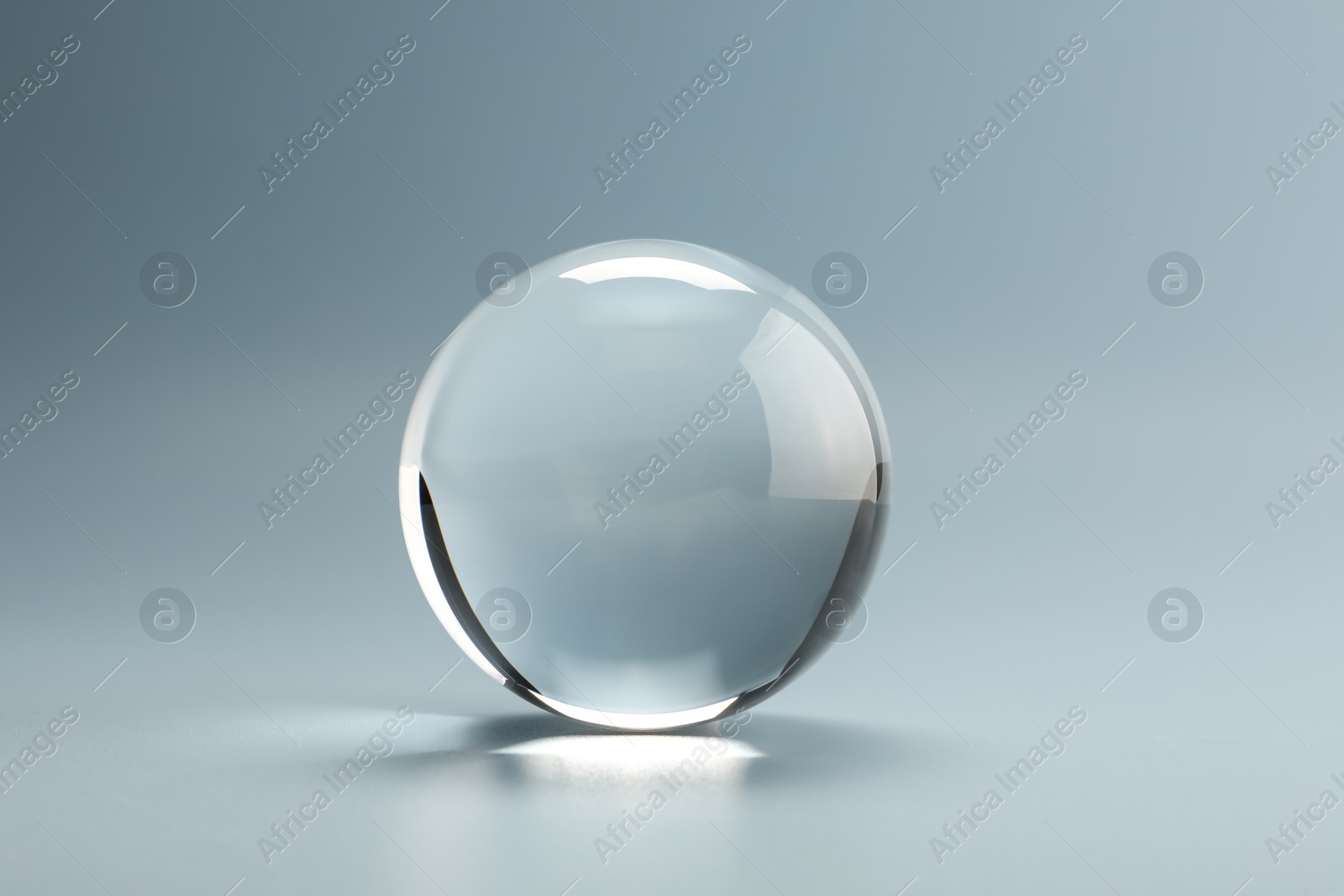 Photo of Transparent glass ball on light grey background