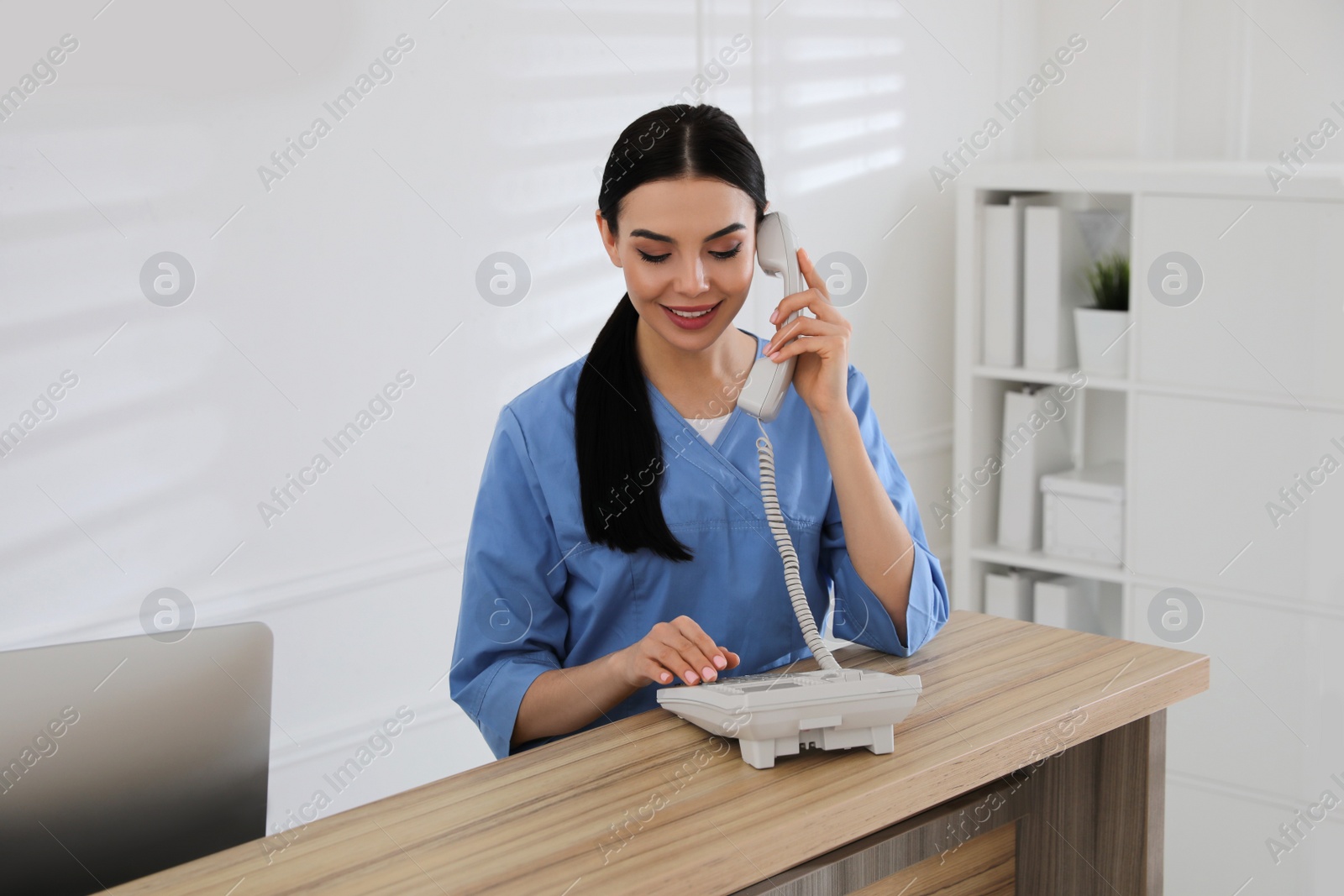 Photo of Receptionist talking on phone at countertop in hospital