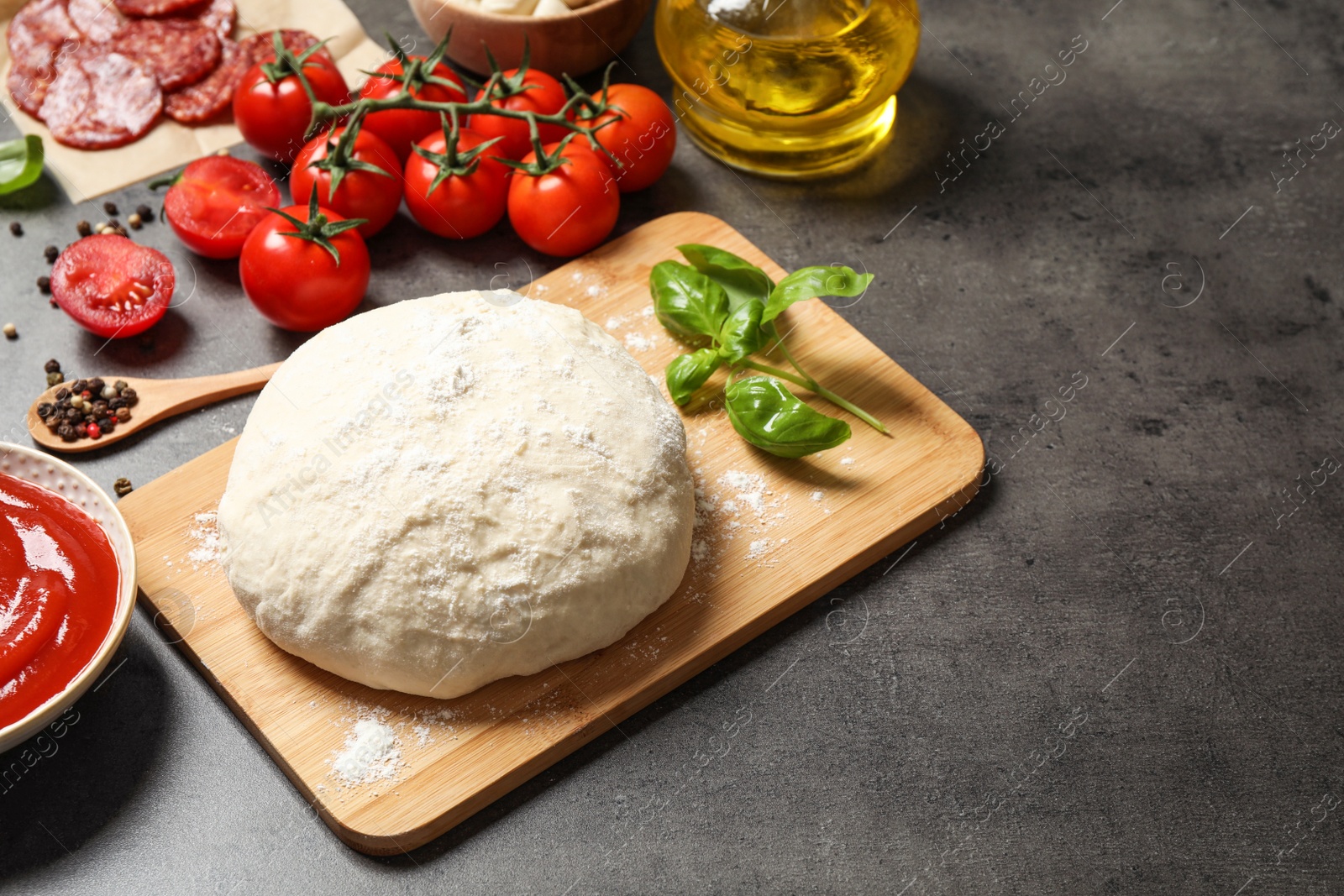 Photo of Dough and fresh ingredients for pepperoni pizza on grey table