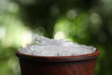 Menthol crystals in bowl against blurred background, closeup. Space for text