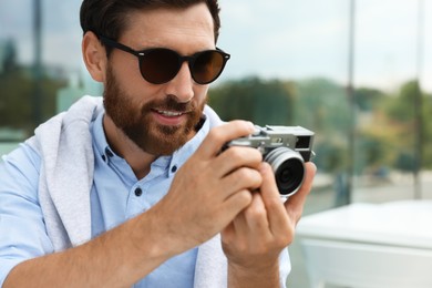 Man with camera taking photo outdoors. Interesting hobby