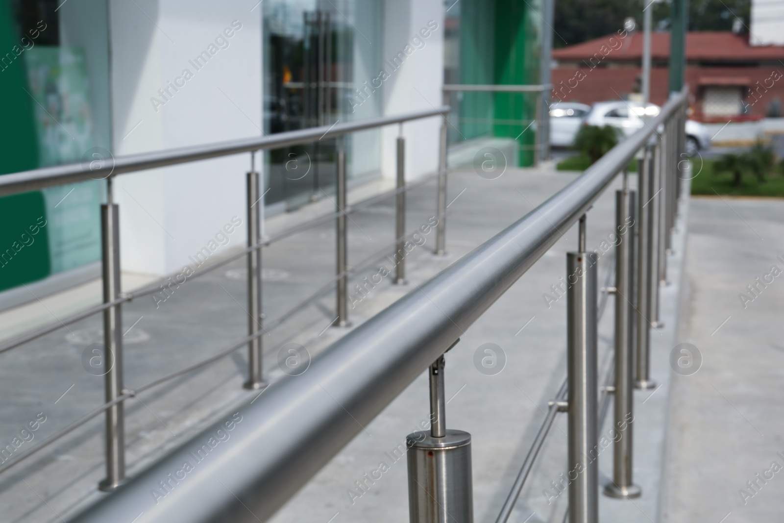 Photo of Concrete ramp with metal handrail near building outdoors, closeup