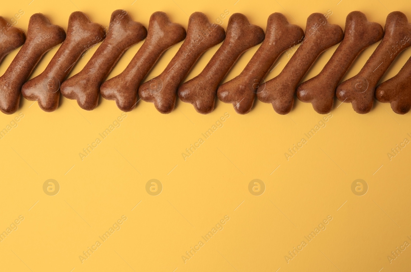 Photo of Bone shaped dog cookies on orange background, flat lay. Space for text