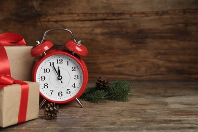 Christmas gifts and alarm clock on wooden table, space for text. Boxing day