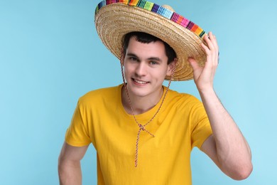 Young man in Mexican sombrero hat on light blue background