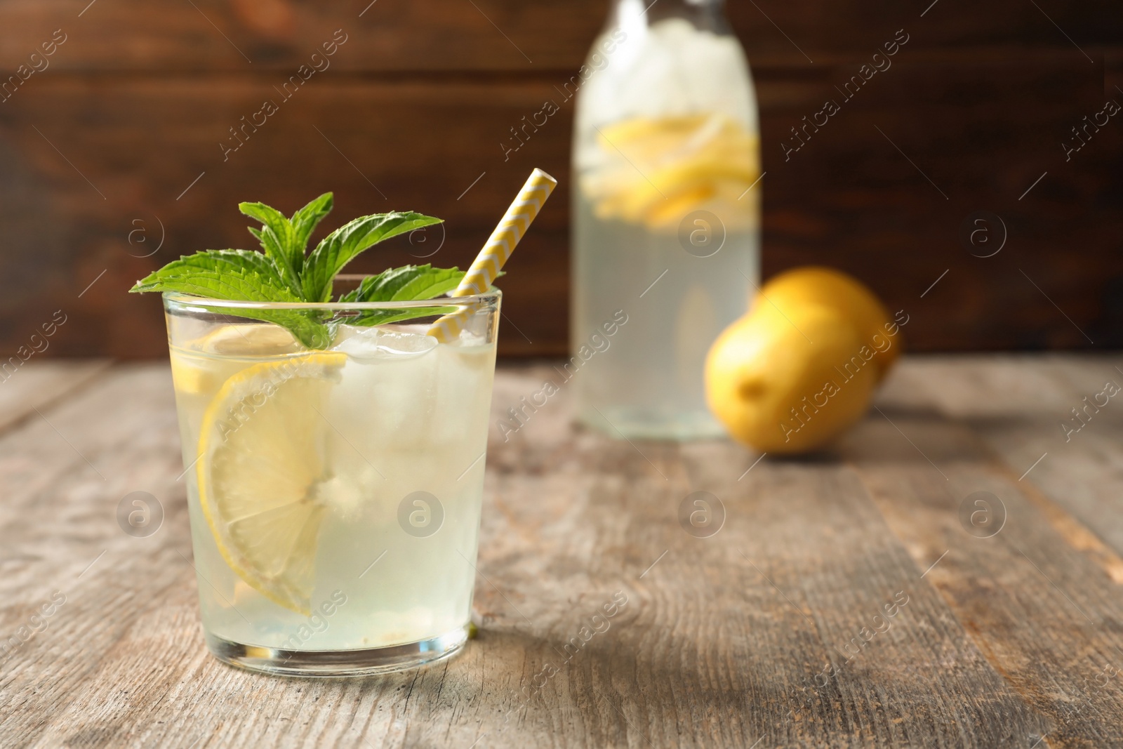 Photo of Natural lemonade with mint in glass on wooden table