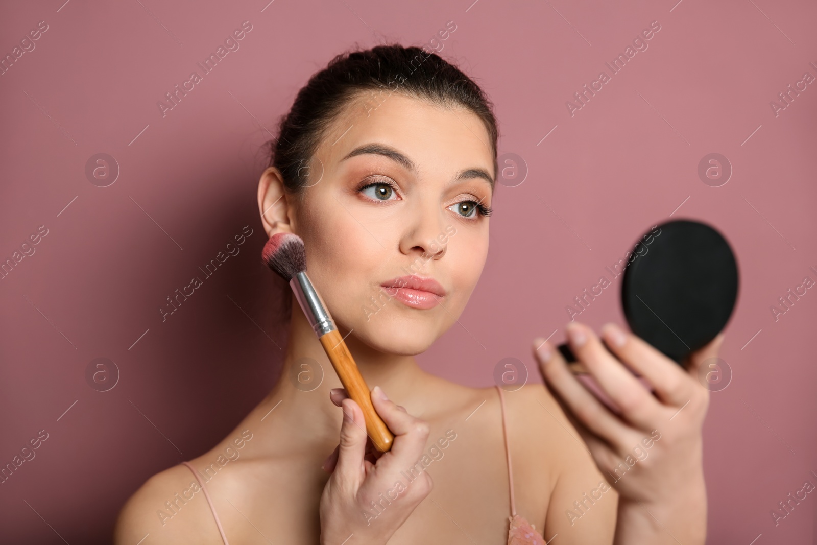 Photo of Young woman applying makeup on color background. Professional cosmetic products