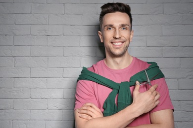 Professional hairdresser with scissors on brick wall background