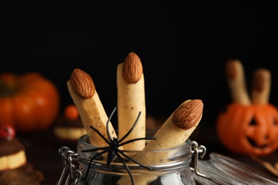 Photo of Delicious desserts decorated as monster fingers on dark background, closeup. Halloween treat