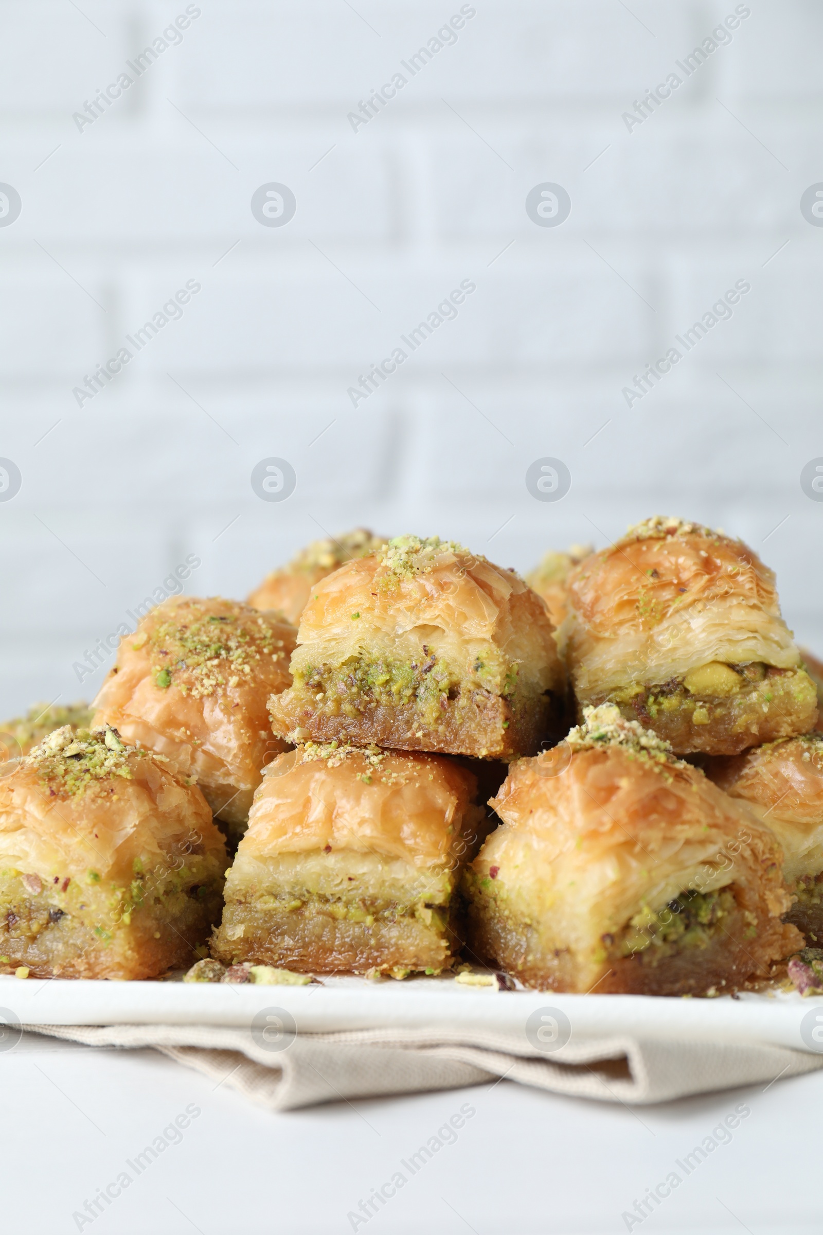 Photo of Delicious fresh baklava with chopped nuts on white table, closeup. Eastern sweets